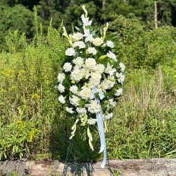 White floral standing spray on a metal easel outdoors