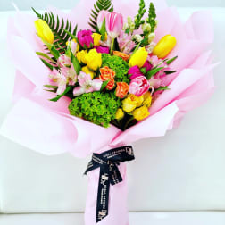 Mixed bouquet of tulips, roses, and alstroemeria wrapped in pink paper