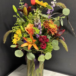 Mixed bouquet in a glass vase with roses, lilies, and sunflowers