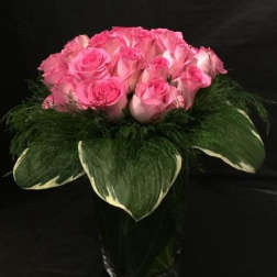 Pink roses arranged in a bouquet with large green leaves