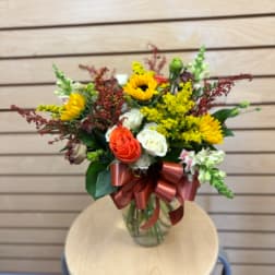 Mixed bouquet with sunflowers, roses, and a ribbon in a glass vase