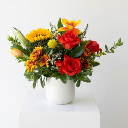 Mixed bouquet of red roses and yellow flowers in a white vase