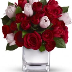 Red and pale pink roses arranged in a clear glass vase