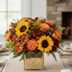 Autumn centerpiece with sunflowers, orange roses, and mums in a square gold vase