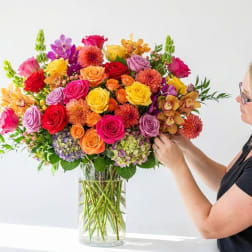 Large mixed bouquet of colorful roses and orchids in a glass vase