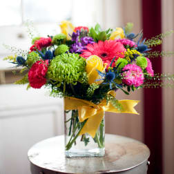 Colorful bouquet in a clear glass vase with a yellow ribbon