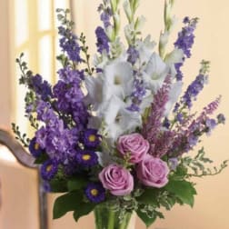 Tall bouquet of purple and white flowers in a clear glass vase
