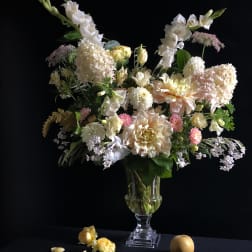 Tall pastel floral arrangement in a clear glass vase with white and blush blooms