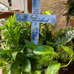 Green potted plant arrangement with a memorial cross sign