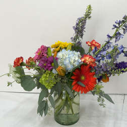 Colorful mixed bouquet in a glass vase with tall purple blooms