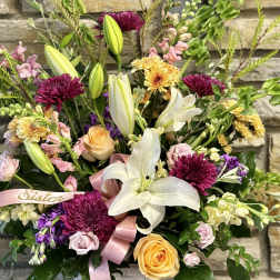 Mixed bouquet in a white basket with lilies, roses, and chrysanthemums