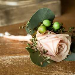 Single blush rose boutonniere with green berries and eucalyptus