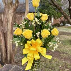 Yellow roses in a glass vase with a large yellow bow