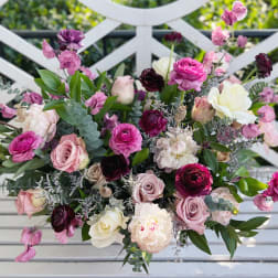Mixed bouquet of pink, white, and burgundy flowers on a white bench
