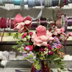 Pink rose bouquet in a purple glass vase with lavender flowers