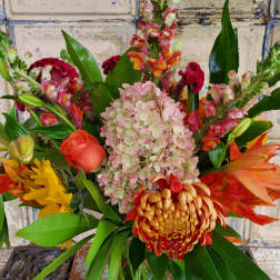 Mixed bouquet with pink hydrangea, orange roses, and tropical blooms