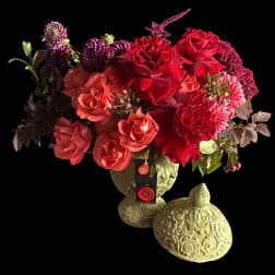 Red and pink roses arranged in a decorative stone vase