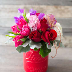 Bouquet of red and pink roses in a red mason jar
