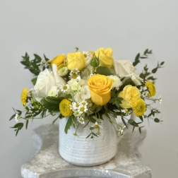 Yellow and white roses arranged in a white vase