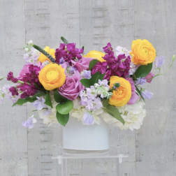 Bouquet of yellow, pink, and lavender flowers in a white vase