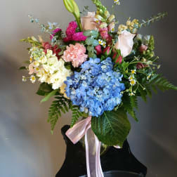 Mixed bouquet with blue hydrangea, roses, carnations, and a pink ribbon