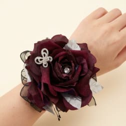 Dark burgundy rose wrist corsage with silver accents on a wrist