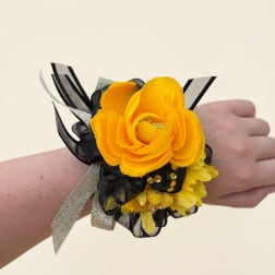 Yellow flower wrist corsage with black and silver ribbon on a wrist
