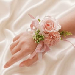 Pink rose and carnation wrist corsage on a hand with ribbon ties