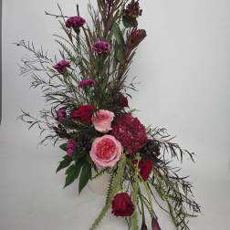 Tall floral arrangement with pink and red roses in a white vase