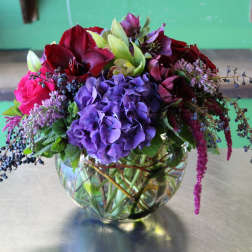 Mixed bouquet of purple, red, and pink flowers in a glass vase