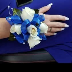 White rose wrist corsage with bright blue ribbon on a person's wrist