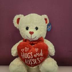 White teddy bear holding a red heart pillow