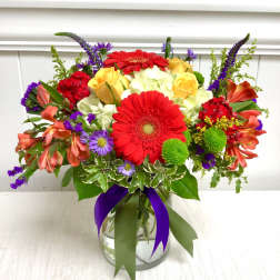 Bright mixed bouquet in a glass vase with red gerbera daisies and yellow roses