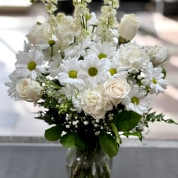 White bouquet of daisies and roses in a clear glass vase