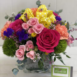 Bouquet of pink and magenta roses with yellow polka-dot ribbon in a glass vase