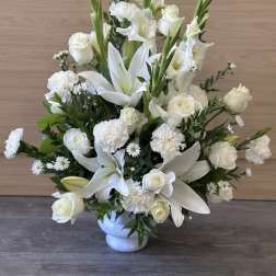 White lilies and roses arranged in a white vase