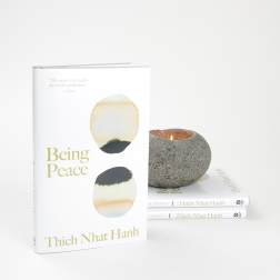Book with a lit stone candle beside two stacked copies