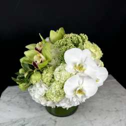 Green and white floral arrangement in a low round vase