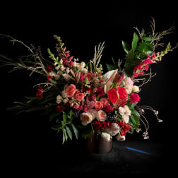 Large floral arrangement with pink and red blooms in a dark vase