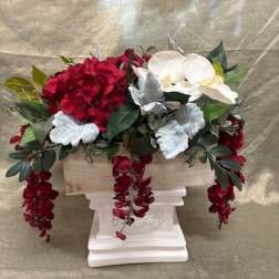 Red and white floral arrangement in a white pedestal container