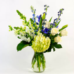 Blue, white, and yellow flowers arranged in a glass vase