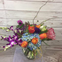 Colorful mixed bouquet in a glass vase with orange roses and blue hydrangea