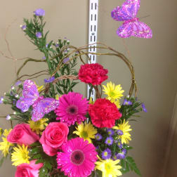 Bright mixed flower basket with pink roses, gerbera daisies, and butterflies