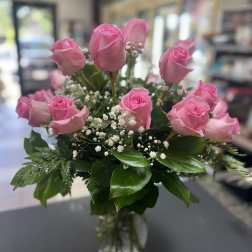 Pink roses arranged in a clear glass vase with baby's breath