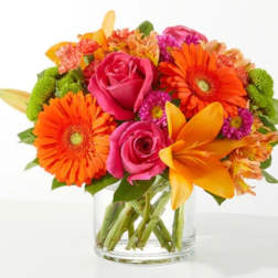 Bright mixed bouquet with pink roses, orange gerberas, and yellow lilies in a glass vase