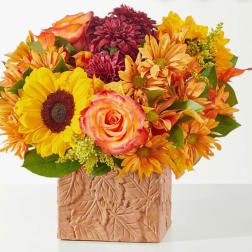 Bouquet of sunflowers, roses, and mums in a leaf-patterned vase