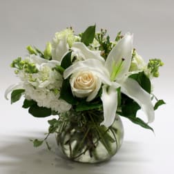 White lilies and a cream rose in a glass vase