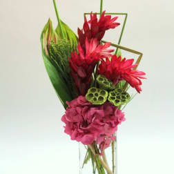 Tropical bouquet with red and pink flowers in a clear glass vase