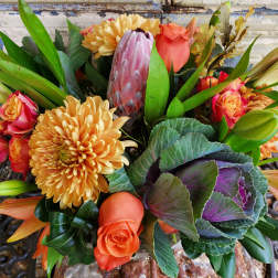 Bouquet of orange roses, yellow chrysanthemums, and a pink protea