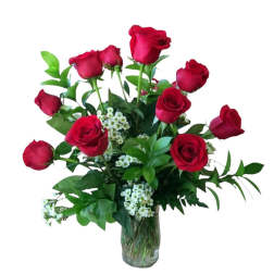 Red roses arranged in a clear glass vase with white filler flowers
